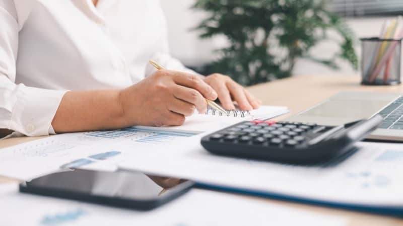Hands planning Meta Advantage+ campaign budgets with a calculator and performance reports